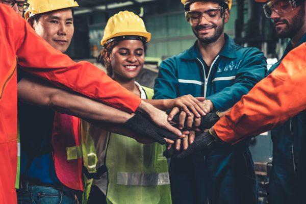 Skillful worker stand together showing teamwork in the factory . Industrial people and manufacturing labor concept .